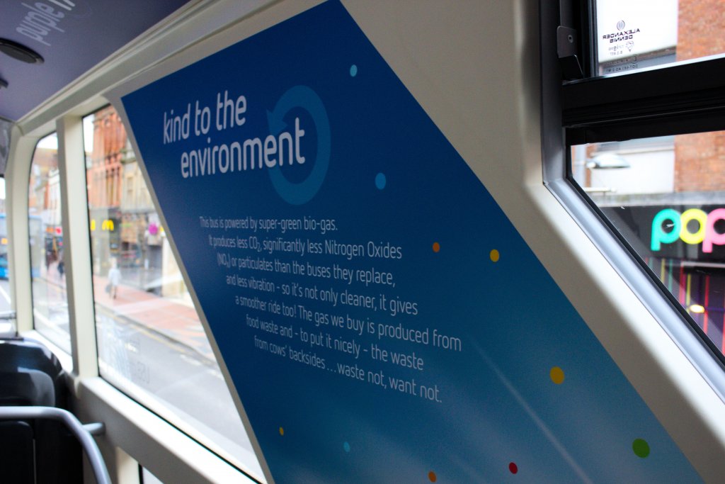 A photograph showing the "Kind to the environment" banner displayed next to the glazed stairwell on the purple 17 buses